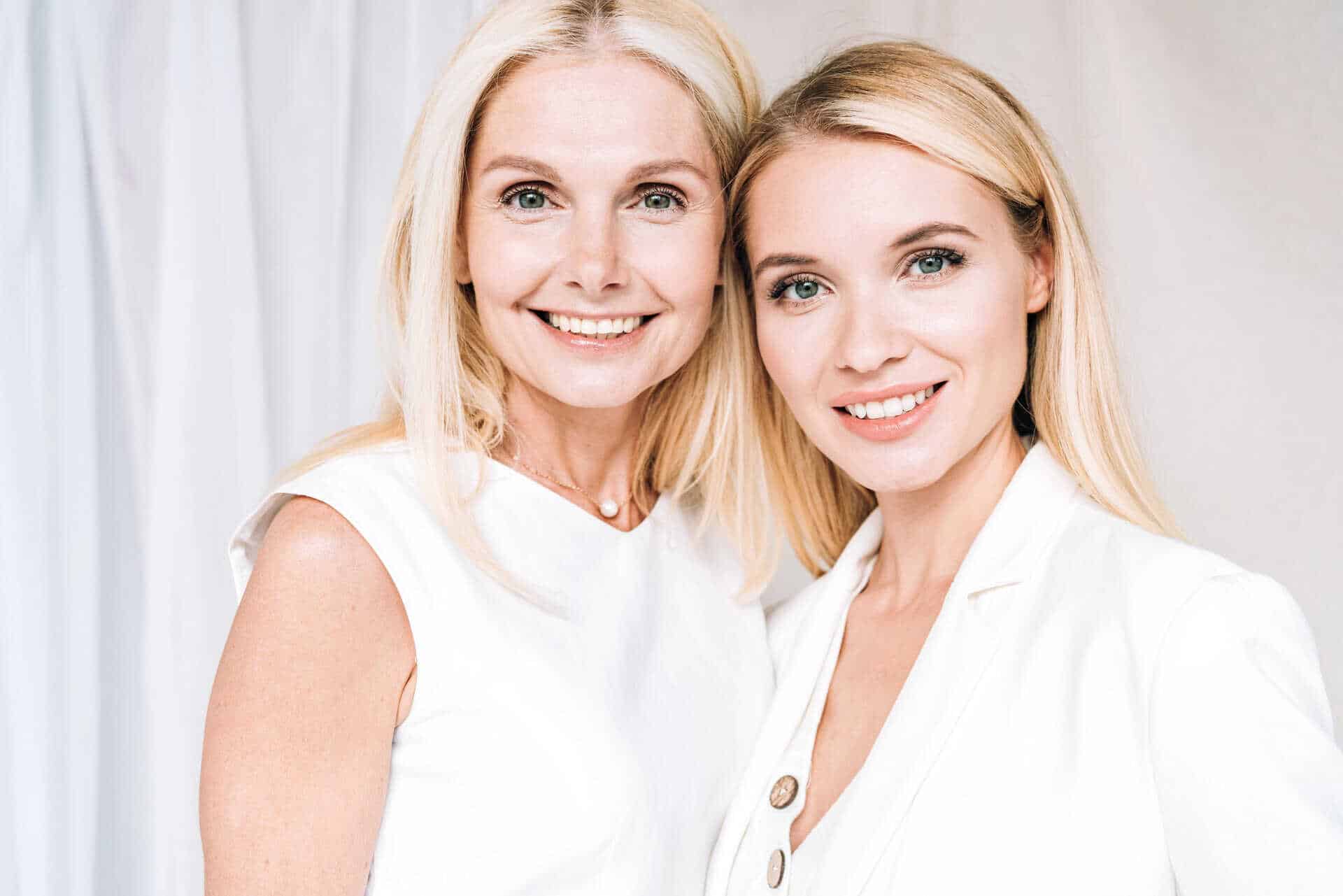 blonde mother and daughter both dressed in white smiling